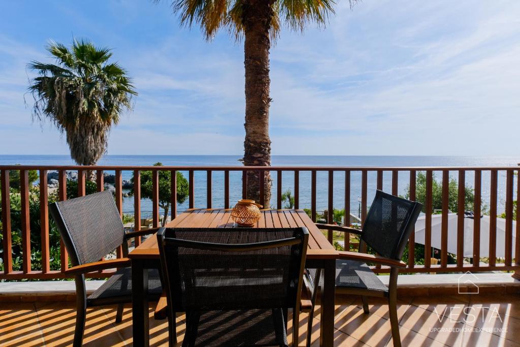 una mesa de madera y sillas en una terraza con la playa en Amphitriti SeaFront Apartments, Loutra Agia Paraskevi en Agia Paraskevi