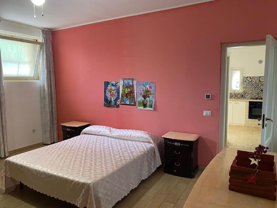 una camera con un letto bianco e una parete rossa di Villa Coco Monopoli a Monopoli