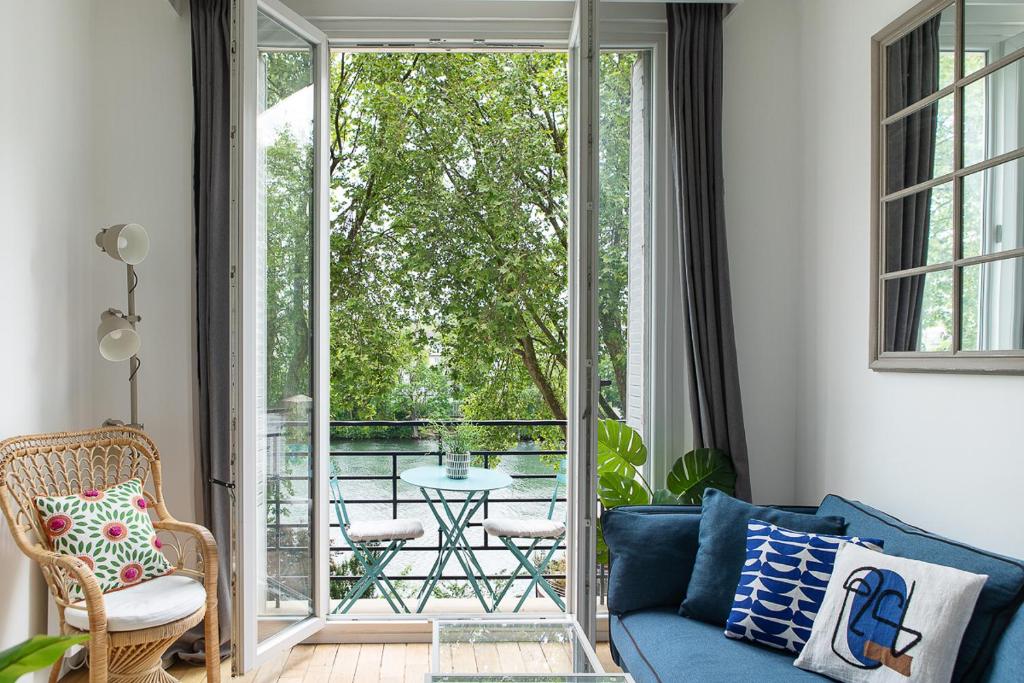 ein Wohnzimmer mit einem blauen Sofa und einem Balkon in der Unterkunft Magnifique appartement avec une très belle vue sur seine in Boulogne-Billancourt