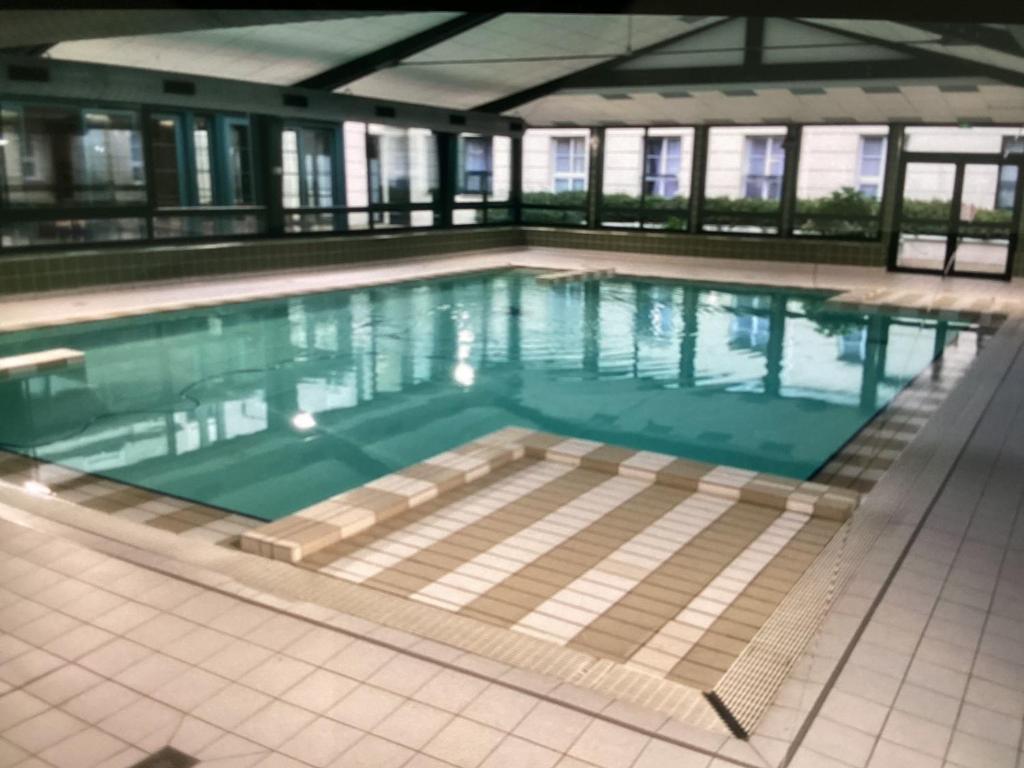 - une grande piscine d'eau bleue dans un bâtiment dans l'établissement APPARTEMENT NEAR DISNEYLAND, à Serris