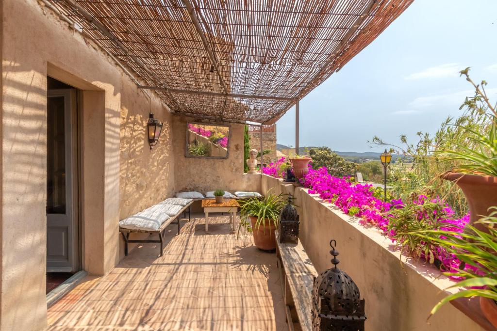 une terrasse avec une table, des chaises et des fleurs dans l'établissement Casa rural siglo xviii, à Pals