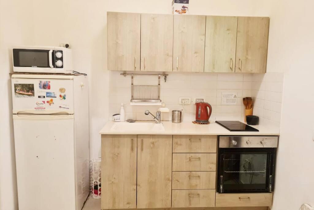 a kitchen with wooden cabinets and a white refrigerator at Best Place to relax in Tel Aviv in Tel Aviv