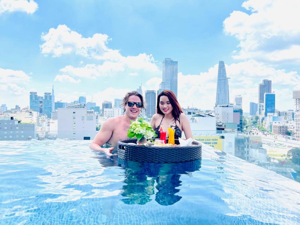 a man and woman in a infinity pool on the roof of a building at Paradise Saigon Boutique Hotel & Spa in Ho Chi Minh City