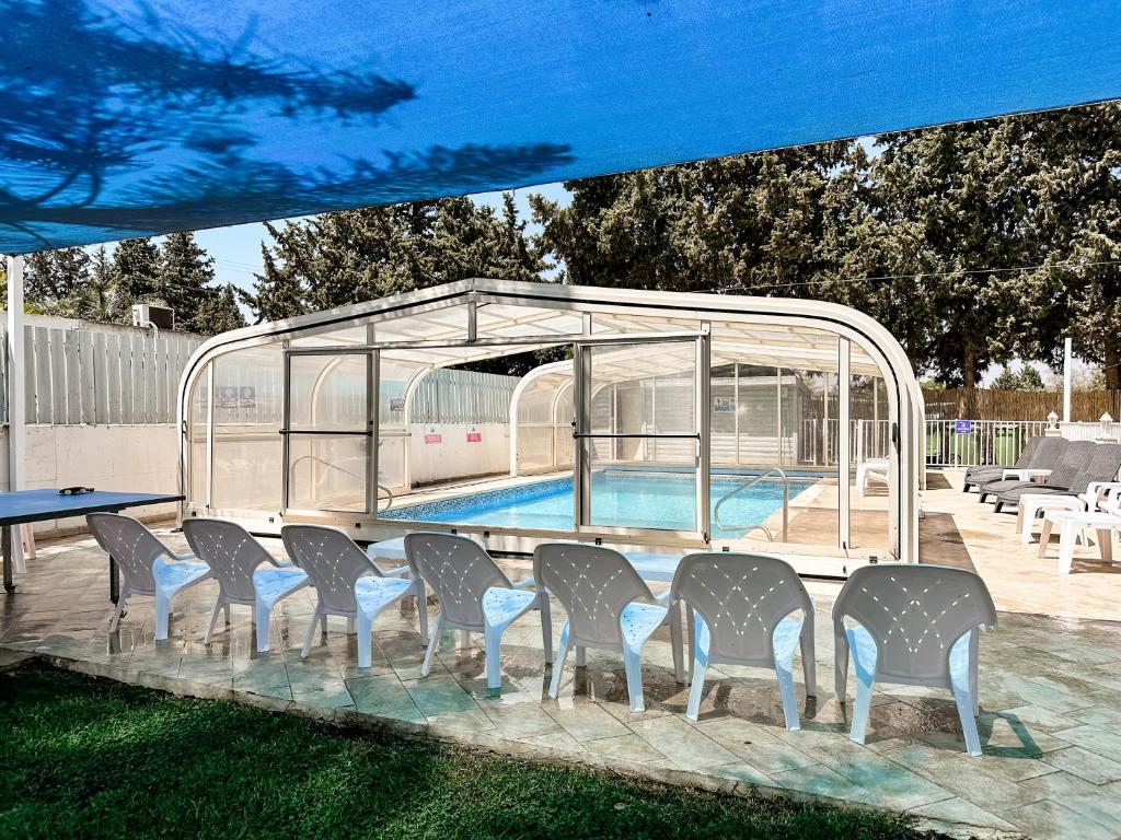 un grupo de sillas y una piscina en un pabellón en Etzel Tami Hospitality, en Neot Golan