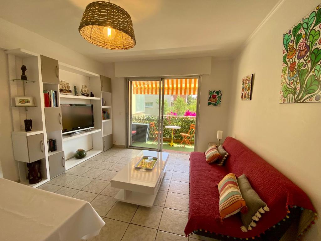 a living room with a red couch and a table at Chez virginie : Appartement lumineux au calme. in Fréjus
