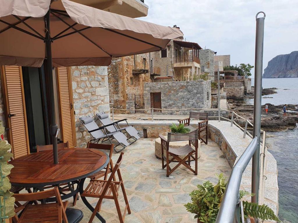eine Terrasse mit einem Tisch, Stühlen und einem Sonnenschirm in der Unterkunft MiloPetra in Yerolimin