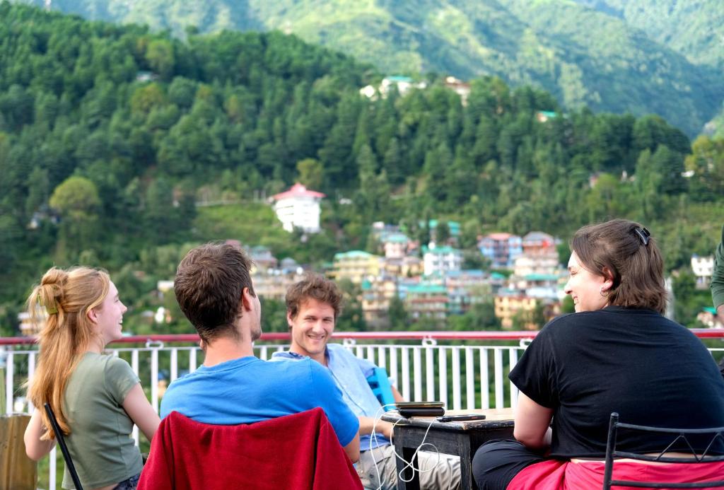 a group of people sitting on a balcony overlooking a city at Mitra Hostel Mcleodganj in McLeod Ganj
