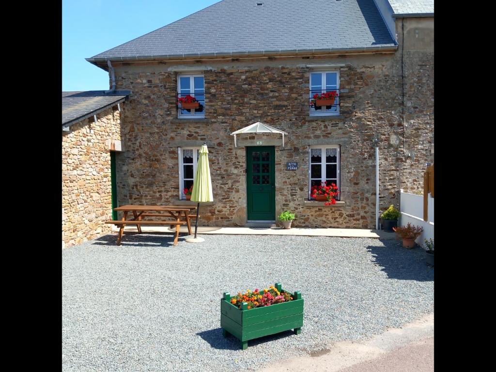 a stone house with a bench and a box of flowers at Gîte de la Forge in Millières