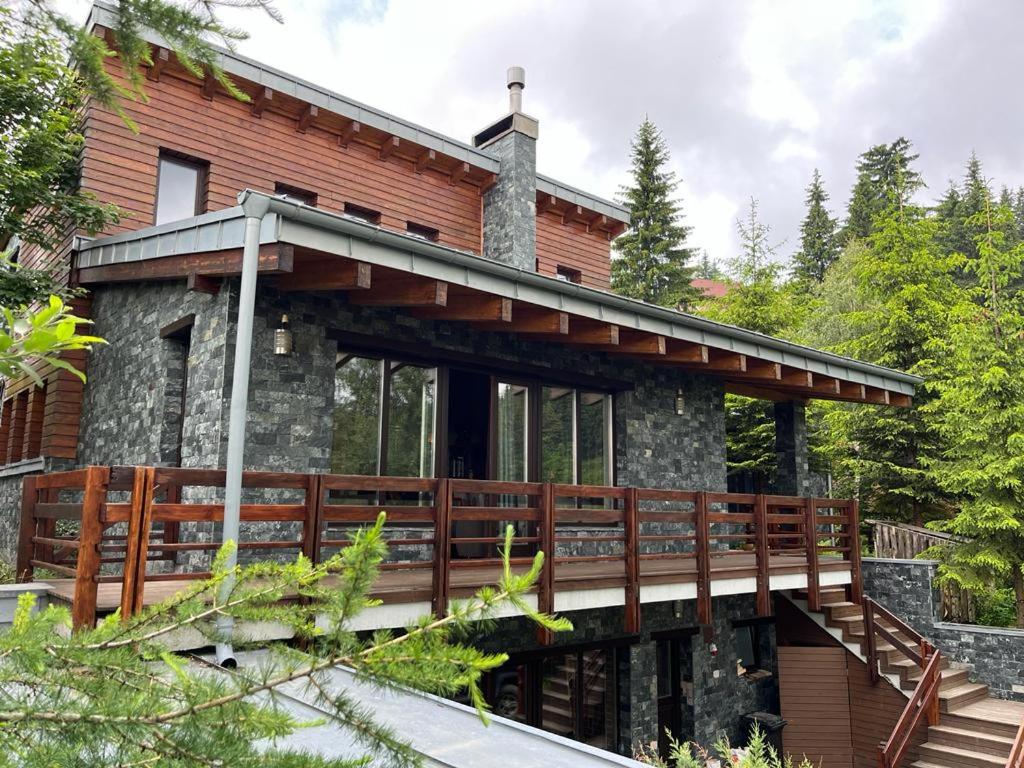 ein Haus mit einer Holzterrasse und einem Balkon in der Unterkunft Bazalt Wellness Villa in Harghita-Băi