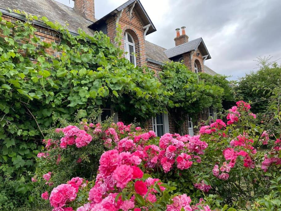 un jardin avec des fleurs roses en face d'une maison dans l'établissement Longère typique perche, à Fontaine-Raoul