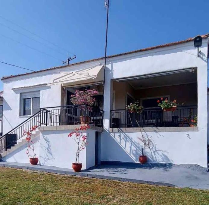 a white house with potted plants on a balcony at zacharenia's home in Mirodháton