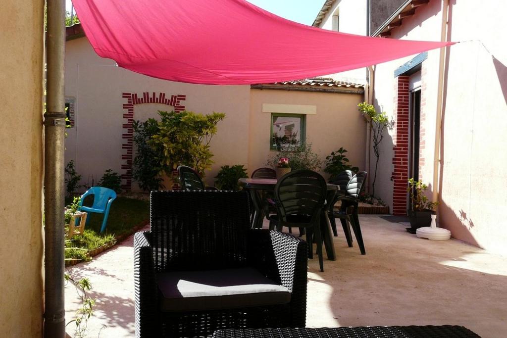 a patio with chairs and tables and a pink canopy at Gîte léperon 4 in Clisson