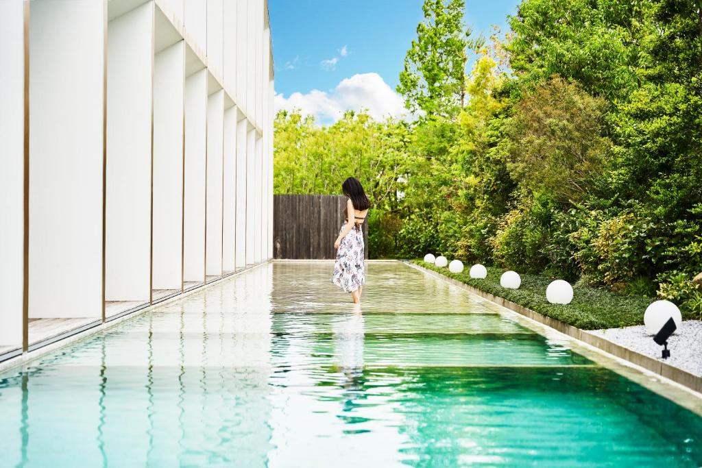 una mujer parada en el agua junto a una piscina en Garden Terrace Saga Hotel & Resorts, en Saga