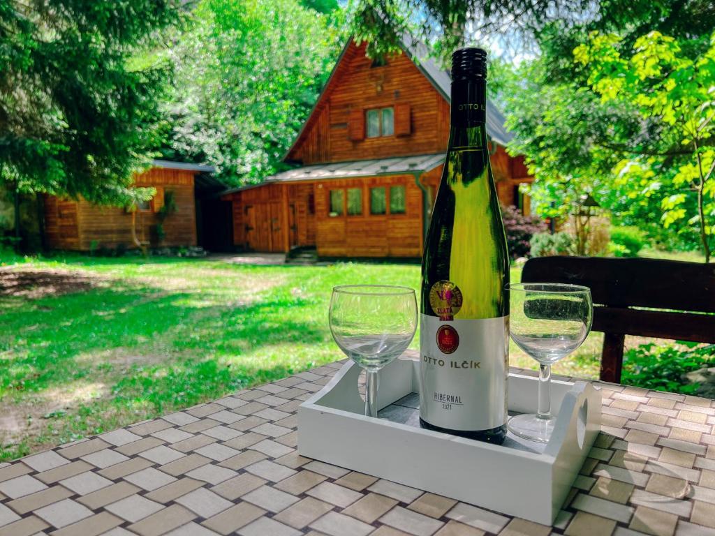 a bottle of wine and two glasses on a table at Hunting lodge under the rock and the river Kretinka in Bystré