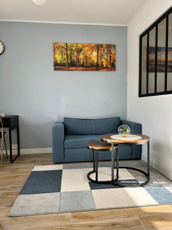 a living room with a blue couch and a table at Cosy studio proche de la Défense in La Garenne-Colombes