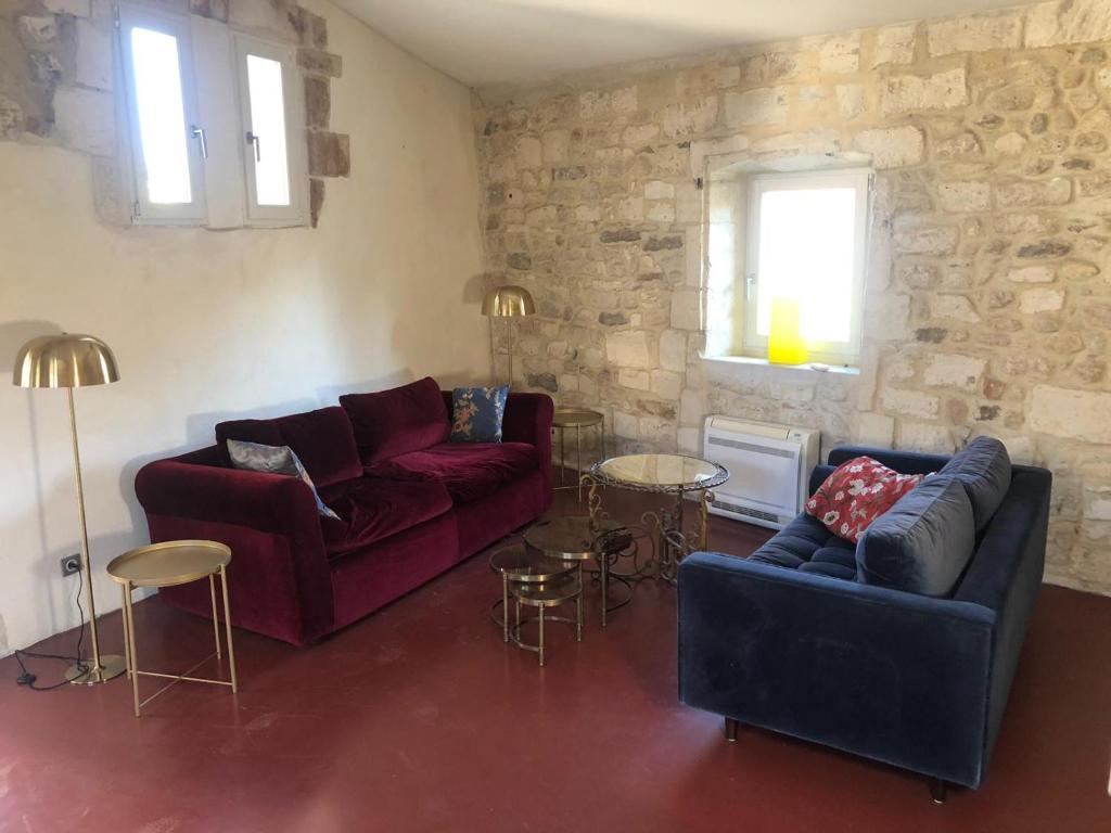 a living room with two couches and a stone wall at Belle maison historique in Arles