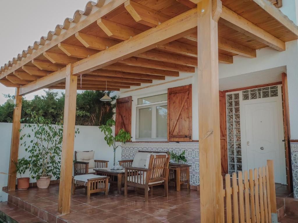 un pergolato in legno con sedie e tavoli su un patio di Casa Familiar Tarragona playa a Tarragona