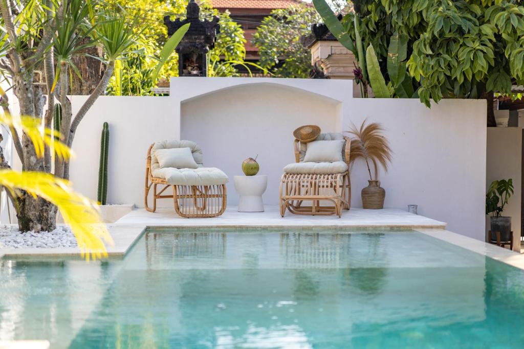 een zwembad met twee stoelen en een tafel en een zwembad bij Cozy Up Villa Sanur in Sanur