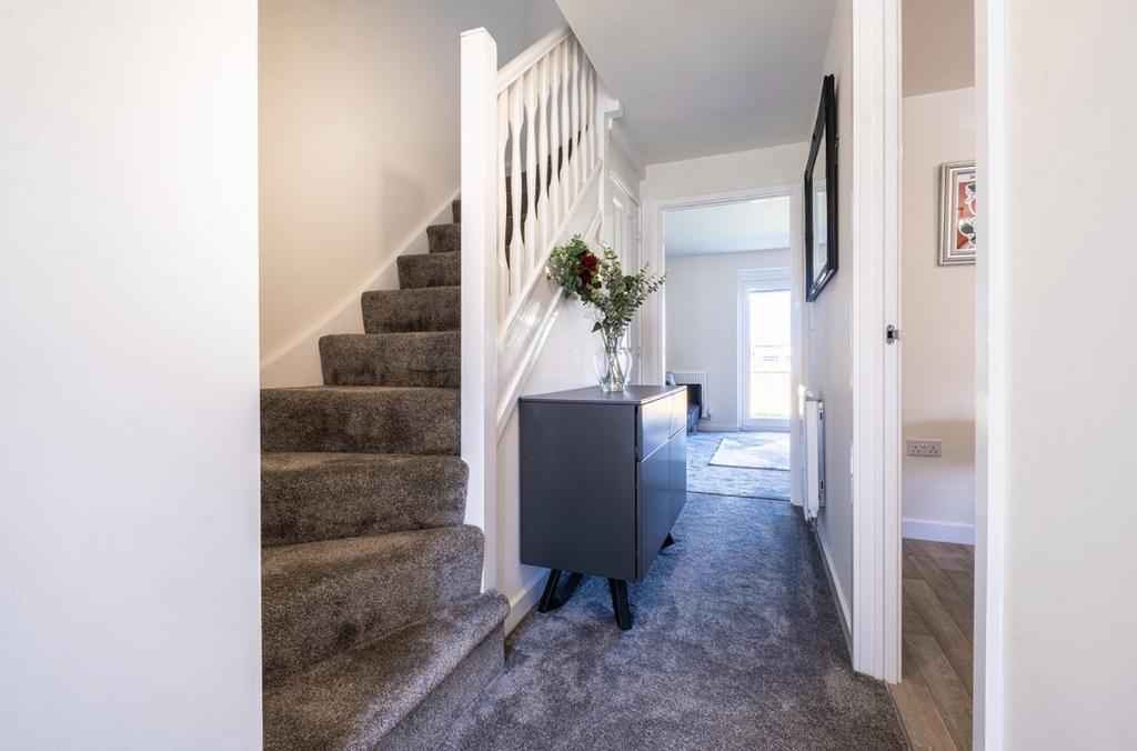 un couloir avec des escaliers et un vase sur une commode dans l'établissement Beautiful Home in Kingston-Upon-Hull, à Hull