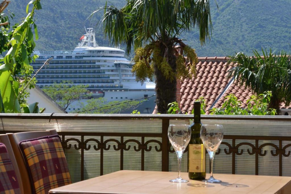 a table with two wine glasses and a cruise ship at Apartments Popovic 2 in Kotor