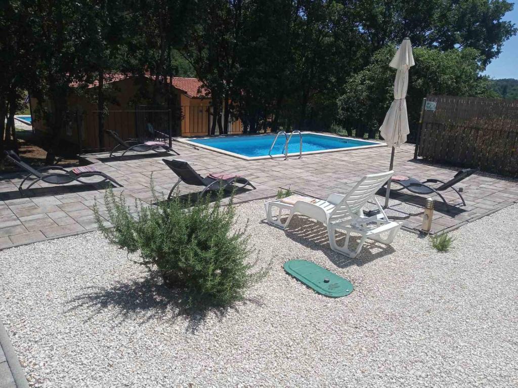 a swimming pool with two lawn chairs and a umbrella at Dee&#39;s House and Pool in Labin