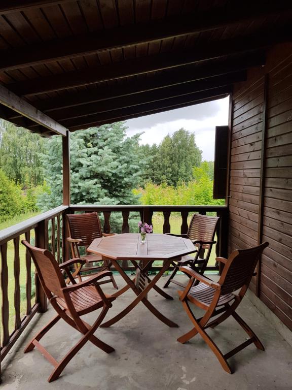 Rybno的住宿－Sarni Zakątek，门廊上的木桌和椅子,配有桌椅