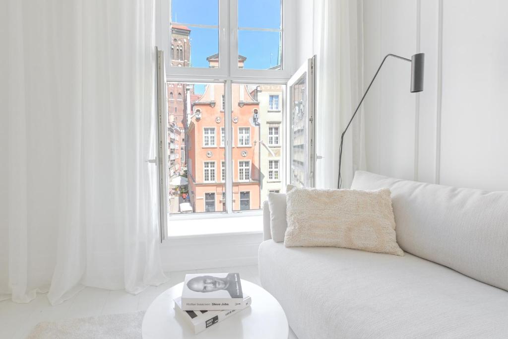 a white living room with a white couch and a window at Downtown Apartments Old Town Pure White in Gdańsk
