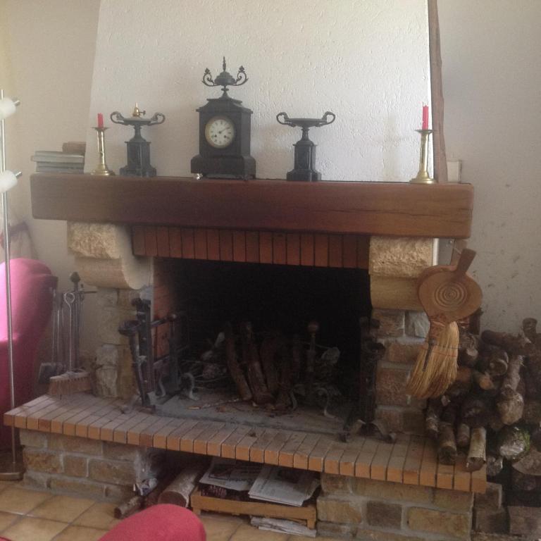 a fireplace with a clock on top of it at Petite maison a l&#39;orée de la foret in Roumégoux