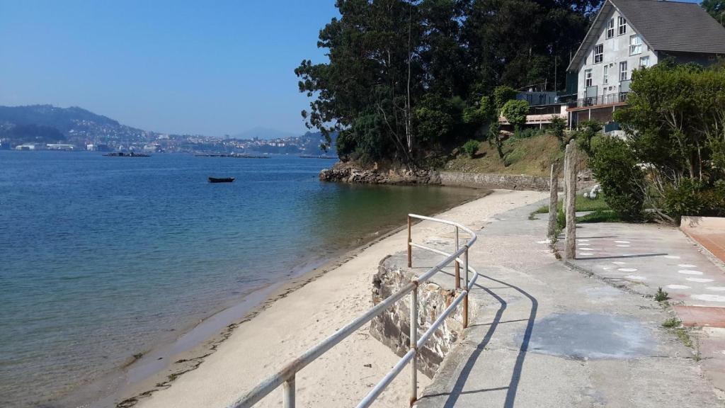 a beach with a metal railing next to the water at Estudio con vistas al mar in Moaña