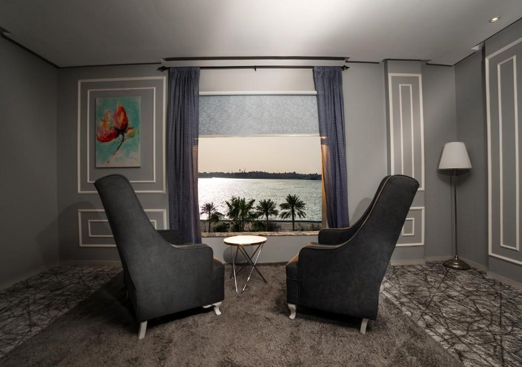 جولدن جاردن الكورنيش للأجنحة الفندقية في الدمام: غرفة معيشة مع كرسيين ونافذة