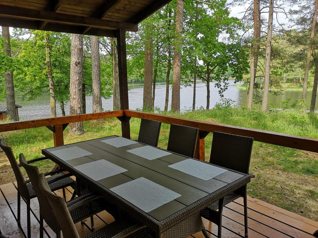 einen Tisch und Stühle auf einer Veranda mit Seeblick in der Unterkunft Osrodek Wypoczynkowy RAJ in Mostowo