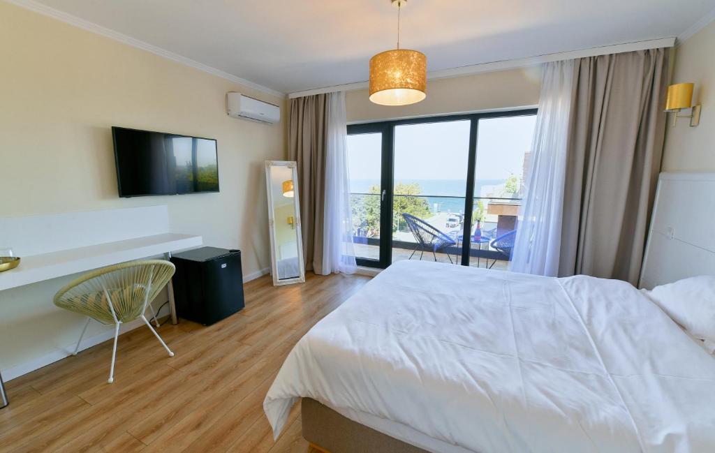 a bedroom with a bed and a tv and a balcony at Vela Olimp in Olimp
