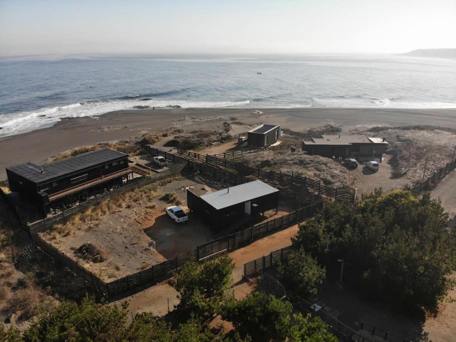 un grupo de edificios en una playa cerca del océano en El Racó - Kitesurf Sirena - Cabaña frente al mar, en Curanipe