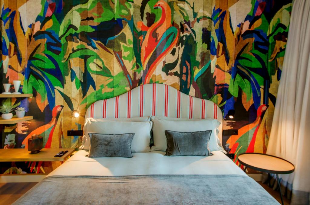 a bedroom with a large bed with a colorful mural at Casa Indiana Hotel Boutique in Blanes