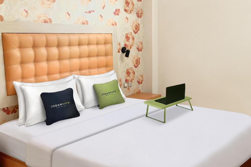 łóżko z 2 poduszkami i laptopem w obiekcie Urbanview Hotel Niraz Syariah Banjarmasin by RedDoorz w mieście Sungai Lutus