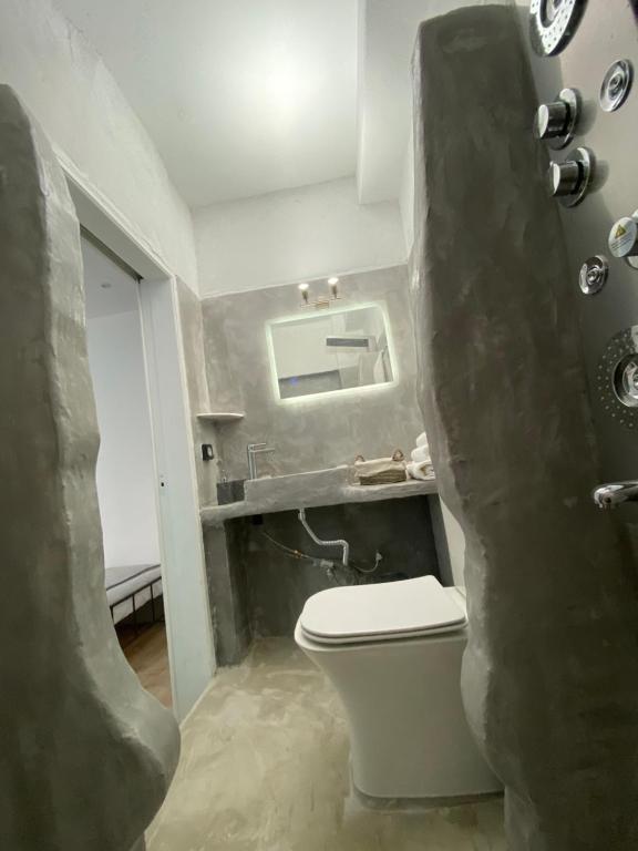 a bathroom with a toilet and a mirror at Cueva Con Vista Studios in Pirgos