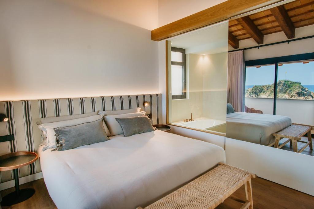 a bedroom with a bed and a tub and a window at Casa Indiana Hotel Boutique in Blanes