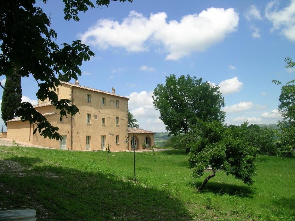 een oud gebouw in een veld met een boom bij La Fonte Carducciana in San Casciano dei Bagni