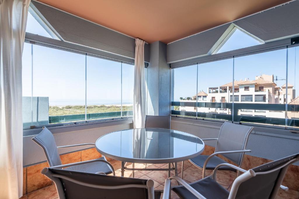 a room with a table and chairs and large windows at Las Palmeras by Ĥ - Playa Punta del Moral PLHP28P11 in Isla del Moral