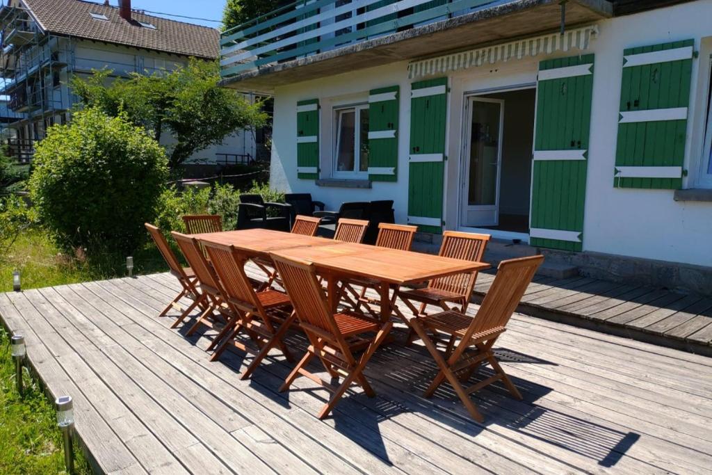 een houten tafel en stoelen op een houten terras bij Apt RDC Au coteau des xettes in Gérardmer