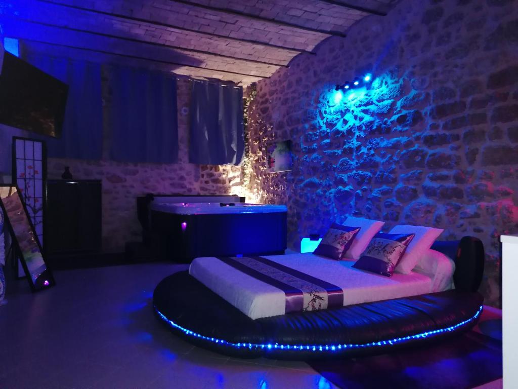 een slaapkamer met een bed in een kamer met blauwe verlichting bij Gîte Love Dreams Jacuzzi privatif in Campagnan