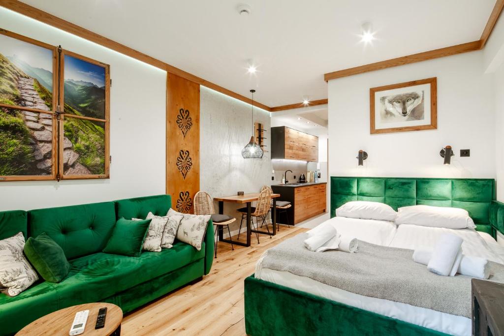 a living room with a green couch and a kitchen at Górskie Szczyty Apart & SPA Apartament 2 Sauna Jacuzzi i Parking w cenie in Zakopane