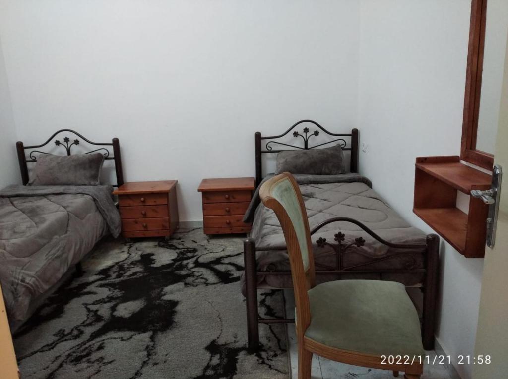 een slaapkamer met 2 aparte bedden en een stoel bij حنضلة درويش in Bethlehem