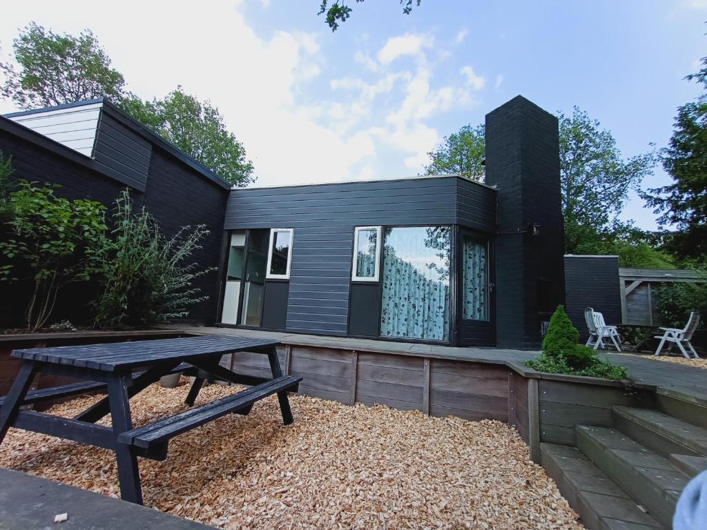 una casa negra con una mesa de picnic delante de ella en Uitrusthuisje en Erm