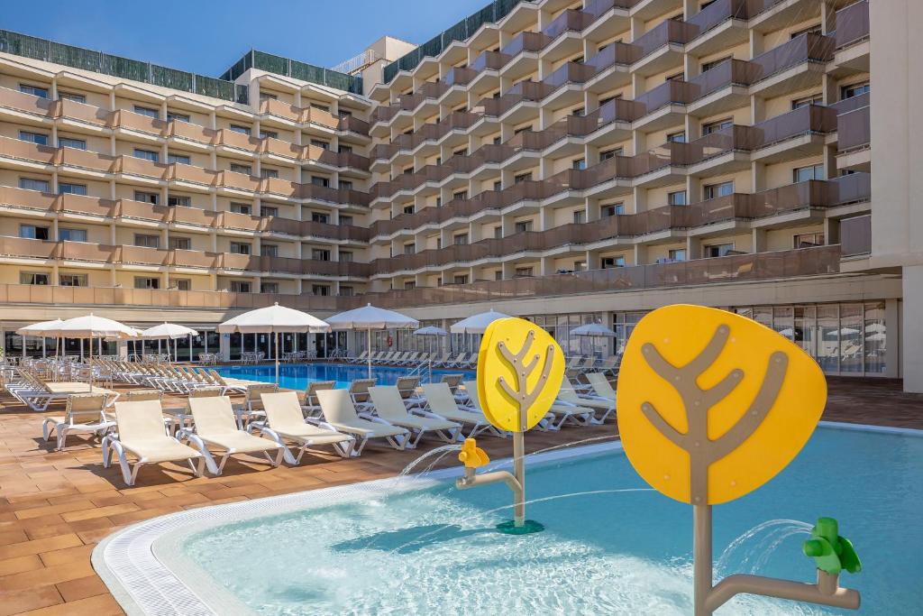 a hotel swimming pool with chairs and a building at htop Amatista #htopBliss in Lloret de Mar