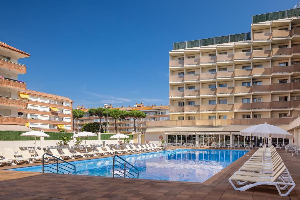 a hotel swimming pool with lounge chairs and a hotel at htop Amatista #htopBliss in Lloret de Mar