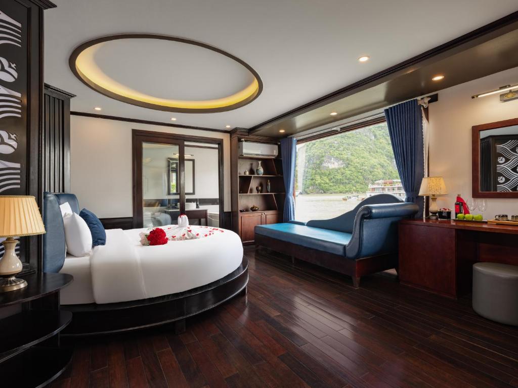 a bedroom with a large white bed and a blue chair at Rosa Cruise in Ha Long