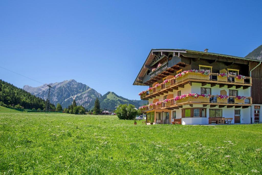 a building in a field with mountains in the background at Landhaus Obertuschenhof in Pertisau
