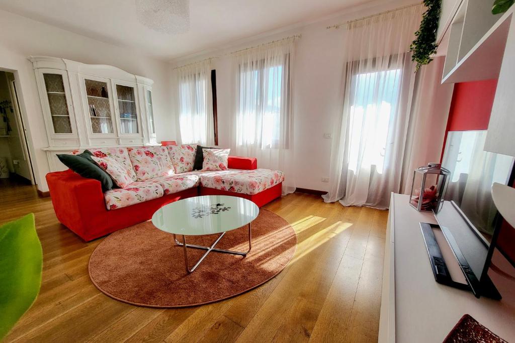 - un salon avec un canapé rouge et une table dans l'établissement Appartamento Lucia, à Vittorio Veneto
