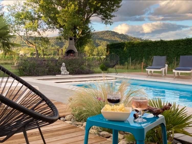 stół z kieliszkami do wina obok basenu w obiekcie Gîte Le vallon des vignes w mieście Vallon-Pont-dʼArc